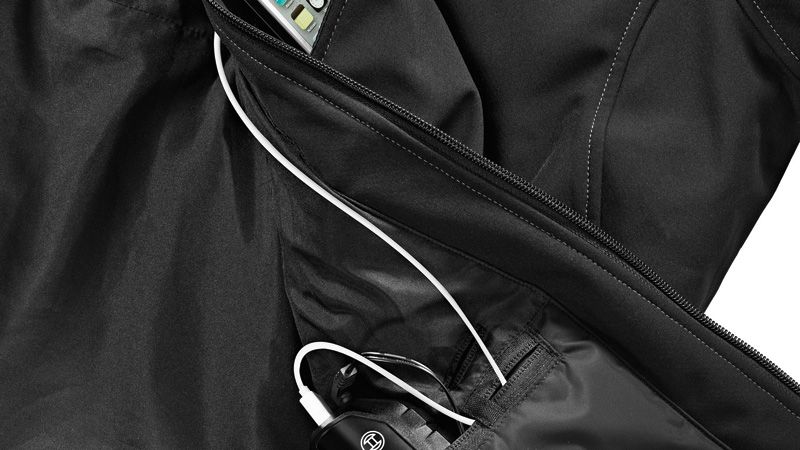 Uma bateria ligada a um dispositivo através de um cabo dentro do bolso de um blusão preto.