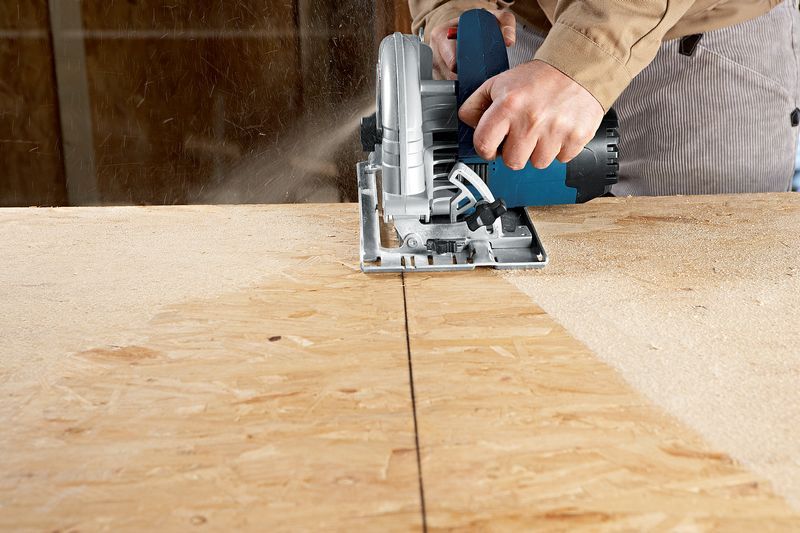 Uma pessoa utiliza uma serra circular manual para cortar uma tábua de madeira.