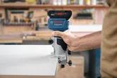 Uma pessoa guia um router sem fios ao longo da borda de um quadro branco.