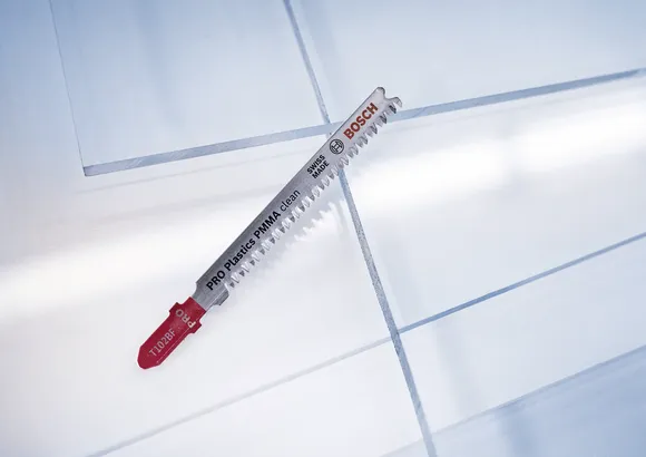 Lâmina de serra tico-tico para cortar folhas de plástico numa superfície de trabalho limpa.