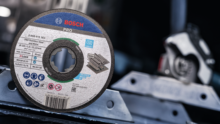 Disco de corte para aço inoxidável colocado sobre uma superfície metálica numa oficina.