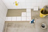Ferramenta de nivelamento a laser projetando linhas vermelhas sobre os azulejos do pavimento.
