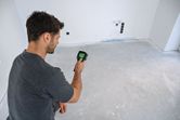 Uma pessoa opera uma câmara termográfica para inspecionar as variações de temperatura num pavimento sem revestimento.