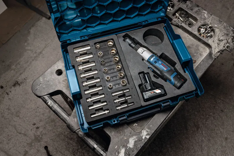Kit de chave de roquete sem fios com tomadas e bateria organizados num estojo de transporte azul.