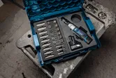 Kit de chave de roquete sem fios com tomadas e bateria organizados num estojo de transporte azul.