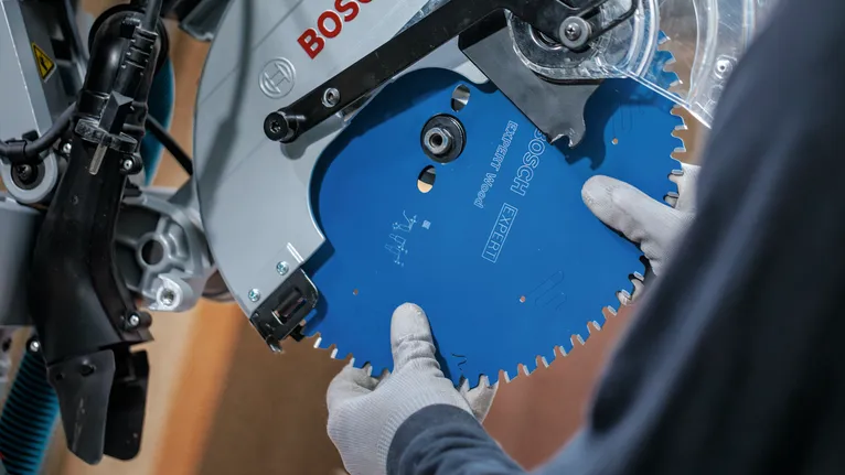 Pessoa que utiliza equipamento de segurança instala uma lâmina de serra circular.