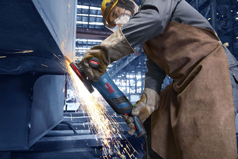 Uma pessoa que usa equipamento de segurança tritura metal, produzindo uma chuva de faíscas.