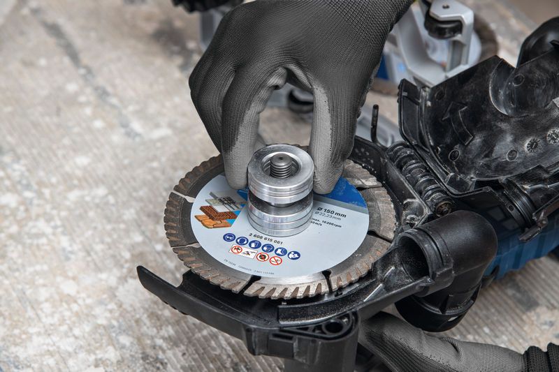 Uma pessoa que utiliza equipamento de segurança instala uma lâmina de corte numa ferramenta de fresagem de paredes.