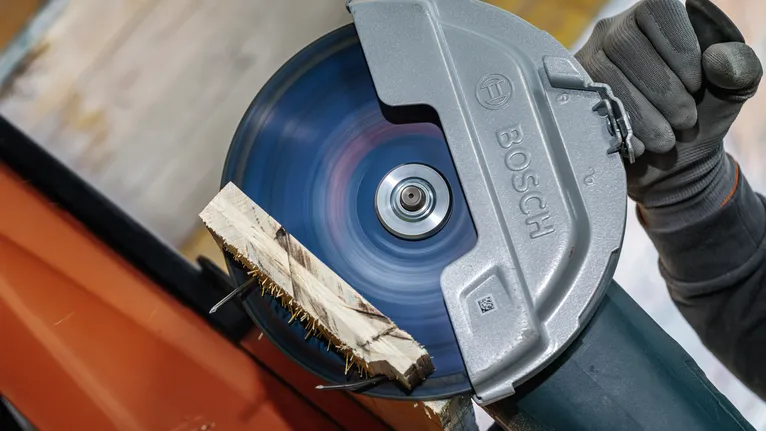 Pessoa que usa equipamento de segurança corta madeira com uma serra circular.