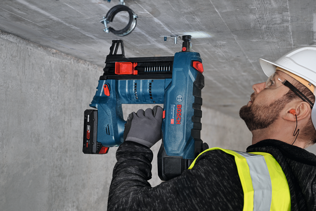 Uma pessoa que utilize equipamento de segurança utiliza uma ferramenta elétrica para instalar um suporte metálico com rosca exterior M8.