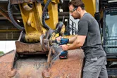 Uma pessoa que utilize equipamento de segurança utiliza uma chave de impacto sem fios em máquinas pesadas.