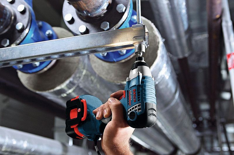 Una persona utiliza un destornillador de impacto inalámbrico para fijar un perno en un marco de metal.