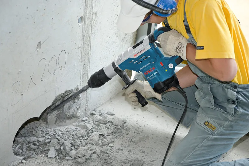 Una persona que usa equipo de seguridad perfora hormigón con un martillo perforador.