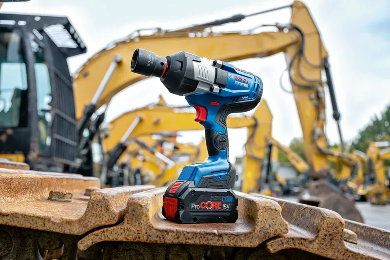 Llave de impacto inalámbrica apoyada sobre orugas de maquinaria pesada en un sitio de construcción.