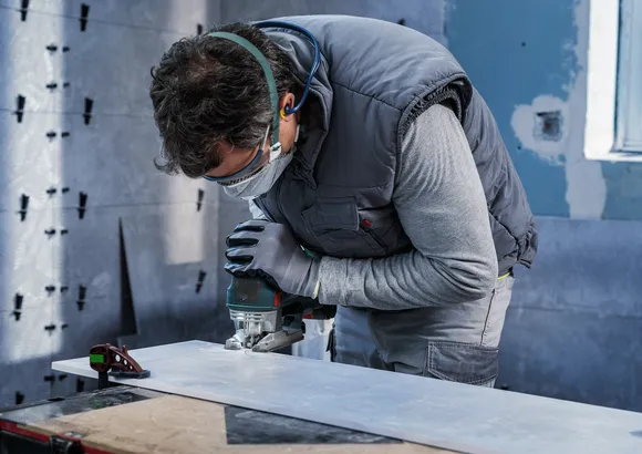 Una persona que usa equipo de seguridad utiliza una sierra caladora para cortar una tabla.