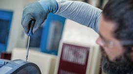 Una persona que lleva puesto un equipo de seguridad aprieta un tornillo con un destornillador manual.