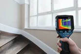 Person uses thermal camera to scan temperature changes near a window.