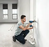 Man drilling wall pipe.