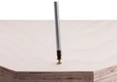 Screwdriver driving a screw into light-colored wood panel.