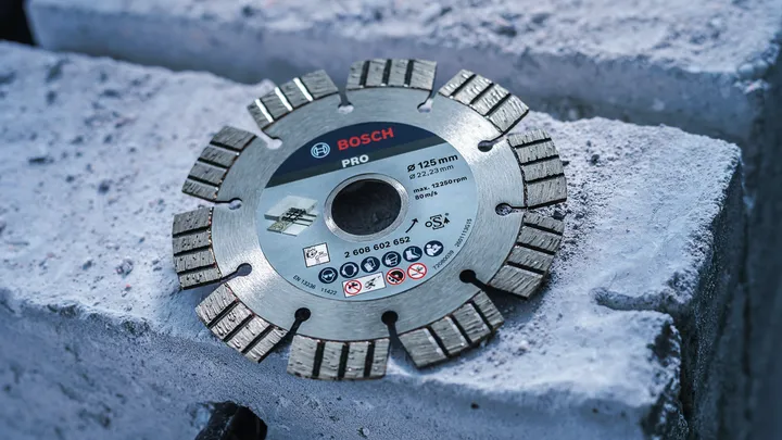 Segmented diamond saw blade resting on concrete blocks.
