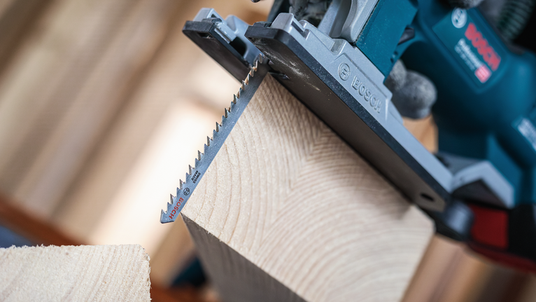 Circular saw slicing through a wooden beam in a workshop.