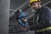 A person wearing safety equipment cuts a threaded rod with a cordless rod cutter.