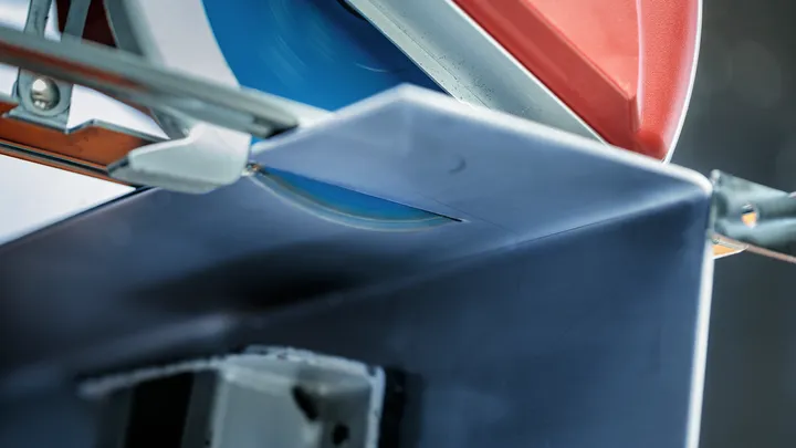A circular saw cuts through a metal beam in a workshop setting.