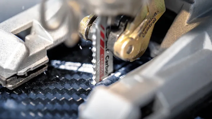 Jigsaw blade cutting through a carbon fiber sheet.
