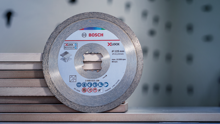 Diamond cutting disc resting on stacked tiles in a workshop setting.