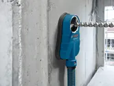 Sistem de extracție a prafului de burghiu atașat la un perete de beton cu un burghiu introdus.