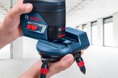 O persoană ajustează un accesoriu pentru nivelarea cu laser într-o cameră luminoasă și nefinisată.