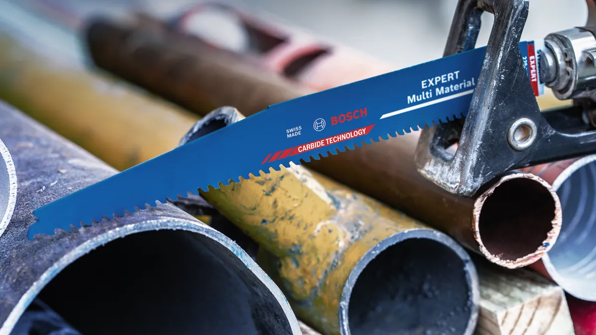 Lamă de ferăstrău alternativ care taie printr-o țeavă metalică într-un atelier.