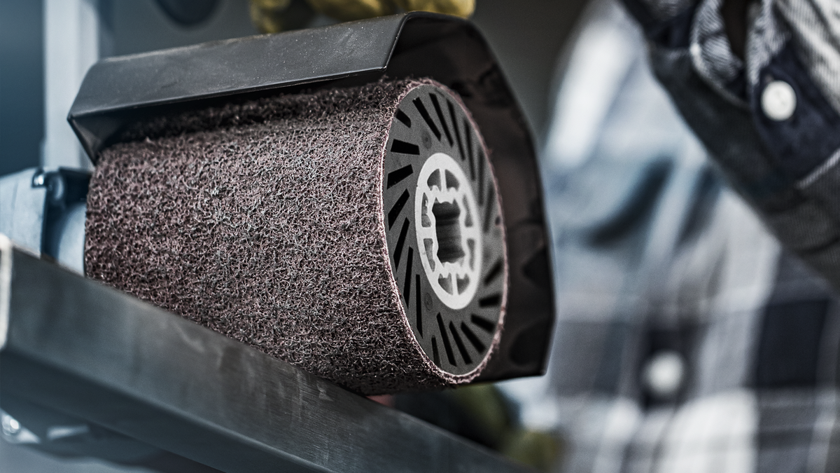 O persoană operează o unealtă electrică cu o roată abrazivă mare pe o suprafață metalică.