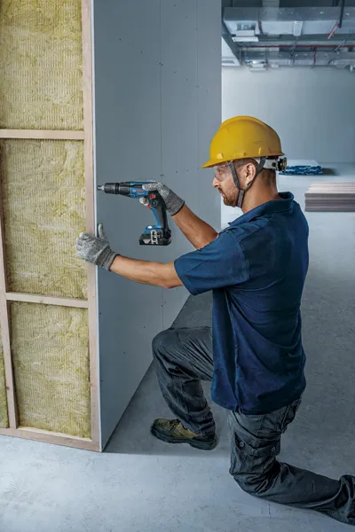 Muncitor instalând panouri de gips-carton.