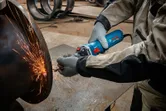 O persoană care poartă echipament de siguranță șlefuiește metalul, creând scântei strălucitoare.