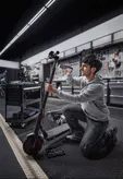 O persoană repară o trotinetă electrică folosind o șurubelniță fără fir într-un atelier.