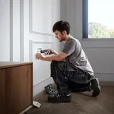 O persoană folosește o șurubelniță fără fir pentru a instala un capac de priză electrică.