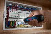 Persoană care folosește o șurubelniță fără fir pentru a strânge șuruburile de pe un panou electric.