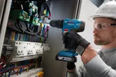 O persoană purtând echipament de siguranță găurește un panou de control plin de fire.