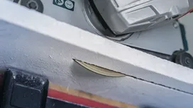 Fierăstrău circular care taie printr-o tablă albă.