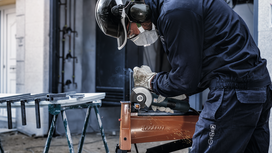 O persoană care poartă echipament de protecție șlefuiește metalul, producând scântei.