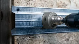 Găuriți cu un ferăstrău circular care taie o grindă metalică.