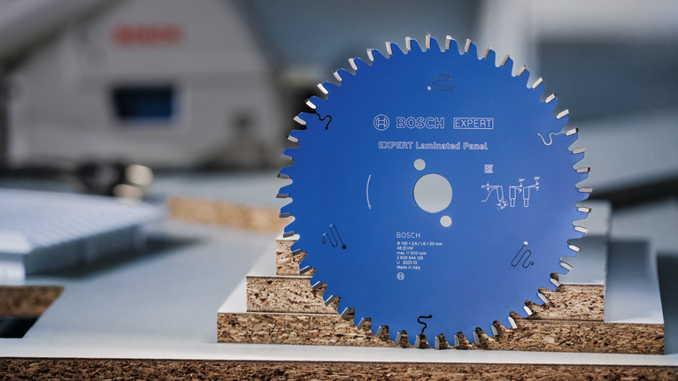 Lamă de ferăstrău circular stând în poziție verticală pe plăci laminate stivuite.