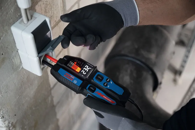 O persoană care poartă echipament de siguranță folosește un tester de tensiune pe cablurile electrice.