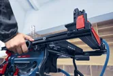 Особа подешава ограду за уздужно сечење на стоној тестеру у радионици.
