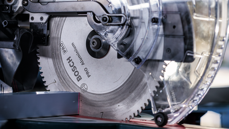 Circular saw blade cutting through a metal piece in a workshop.