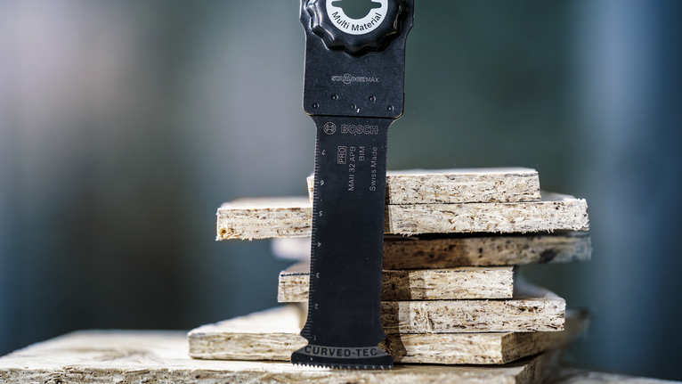Oscillating saw blade positioned on stacked particle boards.