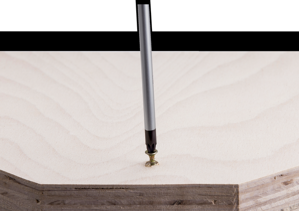 Screwdriver bit driving a screw into a light-colored wooden board.