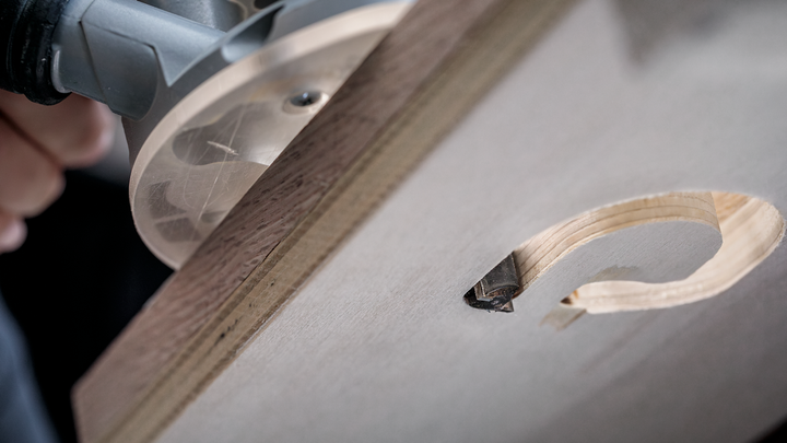 Wood router carving a precise circular hole in a wooden board.