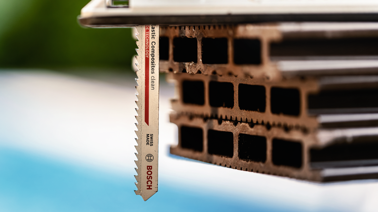 Jigsaw blade cutting through stacked hollow composite material.